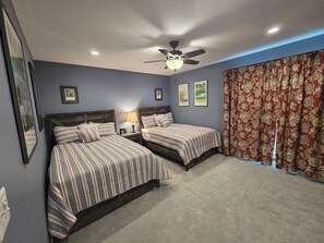A bedroom with two beds, a ceiling fan, and a window with floral curtains. - Reconfigured 2 bedroom, 2 bath condo, walking distance Pinehurst Resort. (Pinehurst)