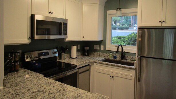 A kitchen with white cabinets, a stainless steel refrigerator, a microwave, an oven, and a window with a view of the outside. - Reconfigured 2 bedroom, 2 bath condo, walking distance Pinehurst Resort. (Pinehurst)