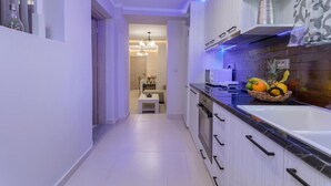 A modern kitchen with white cabinets, a black countertop, and a fruit basket. - Evia s Apartment - New Apartment In Town - Evia s Apartment - New Apartment In Town (Zakynthos)