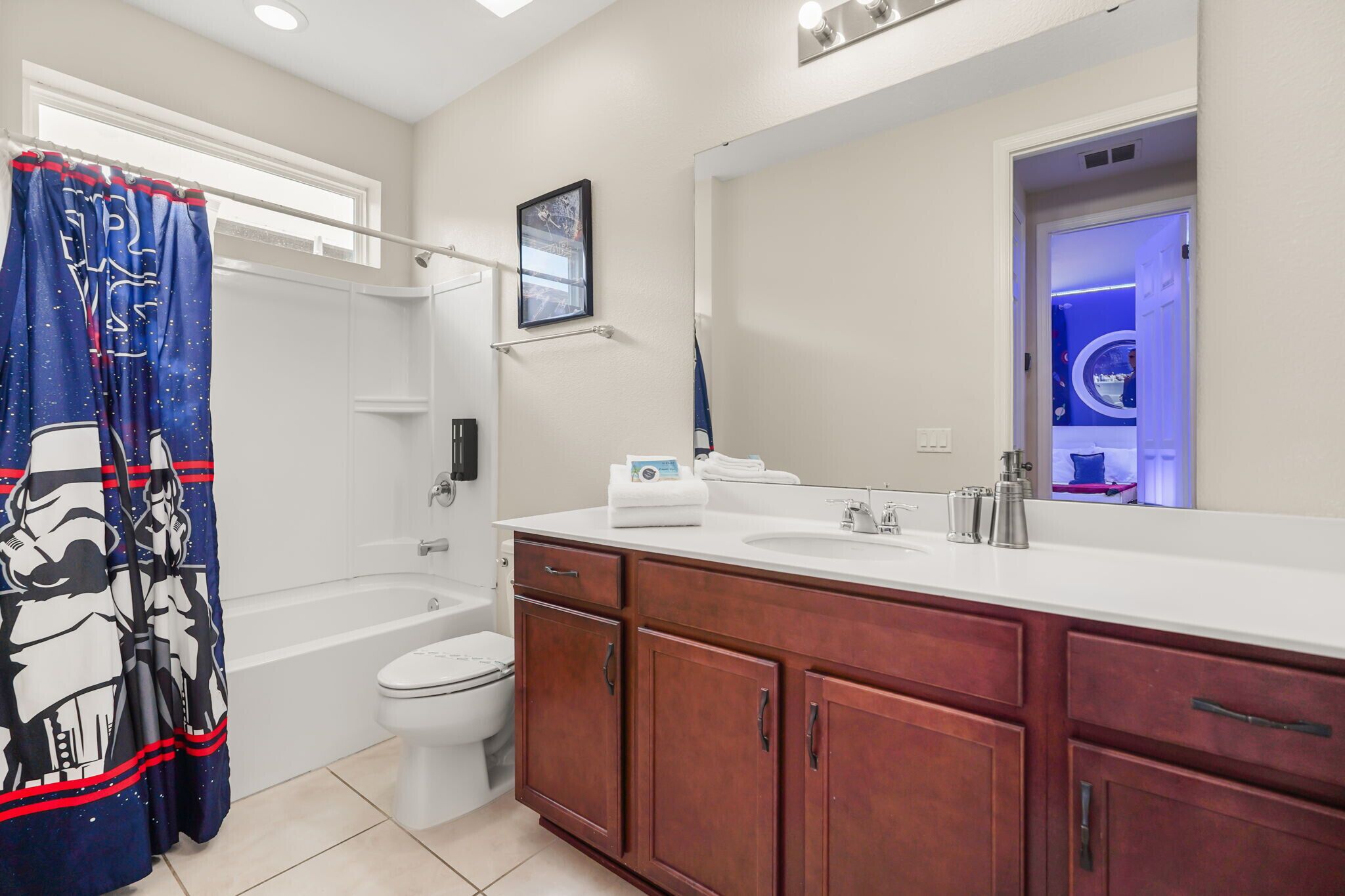 A bathroom with a bathtub, toilet, and vanity with a mirror.