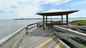 A wooden pier with a covered seating area and a view of the water. - Beachfront condo with gorgeous view of the gulf. (Bradenton Beach)