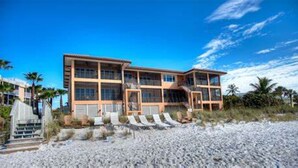 A beachfront property with a multi-story building, a covered patio area, and a sandy beach. - Beachfront condo with gorgeous view of the gulf. (Bradenton Beach)