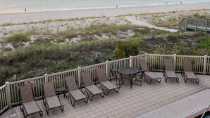 A poolside area with lounge chairs and a view of the beach at sunset. - Beachfront condo with gorgeous view of the gulf. (Bradenton Beach)