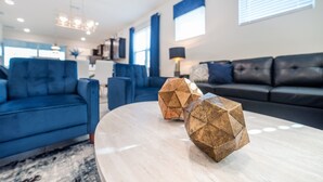 Een moderne woonkamer met een blauwe bank, een zwarte bank en twee geometrische salontafels.