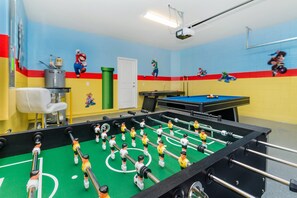 A foosball table in a room with colorful walls and a projector on the ceiling.