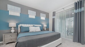 Een moderne slaapkamer met een groot bed, twee nachtkastjes met lampen en uitzicht door middel van kamerhoge ramen.