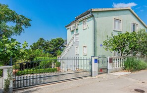 A two-story building with a light green facade, white shutters, and a visible staircase leading to the upper floor. - Gorgeous home in Maslenica (Maslenica)
