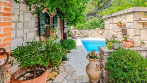 Une cour dallée de pierres, avec une piscine, des plantes en pot et un mur de briques.