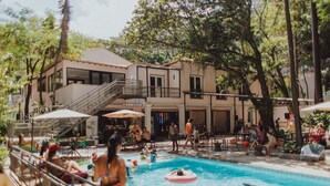 Un espace piscine comprenant un bâtiment à deux étages, des sièges extérieurs et un escalier menant à l’étage supérieur.