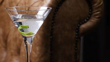 A martini glass with a lime twist on a dark table.