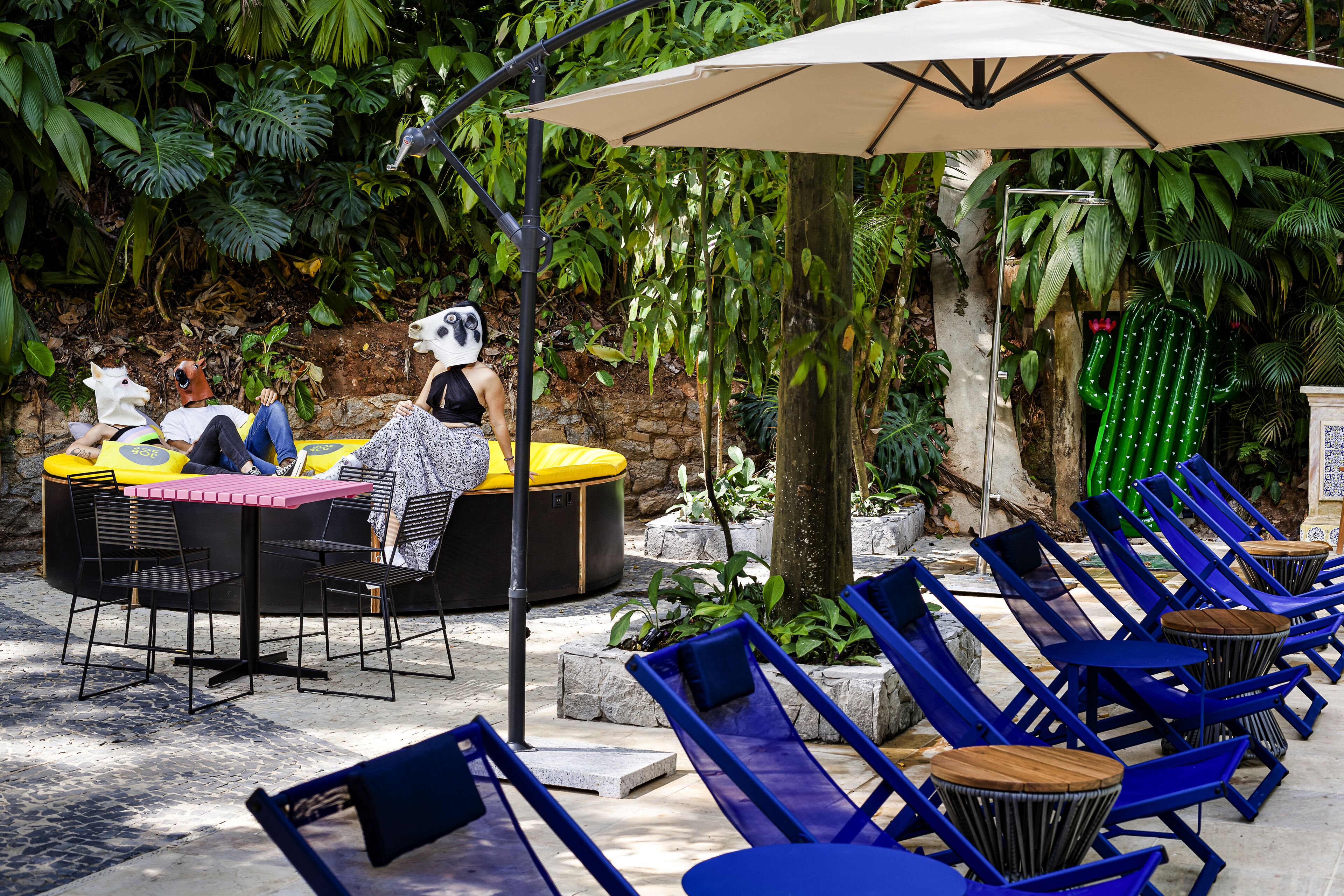 An outdoor seating area with a table and chairs, surrounded by lush greenery.