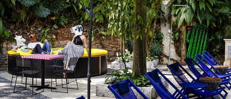 An outdoor seating area with a table and chairs, surrounded by lush greenery.