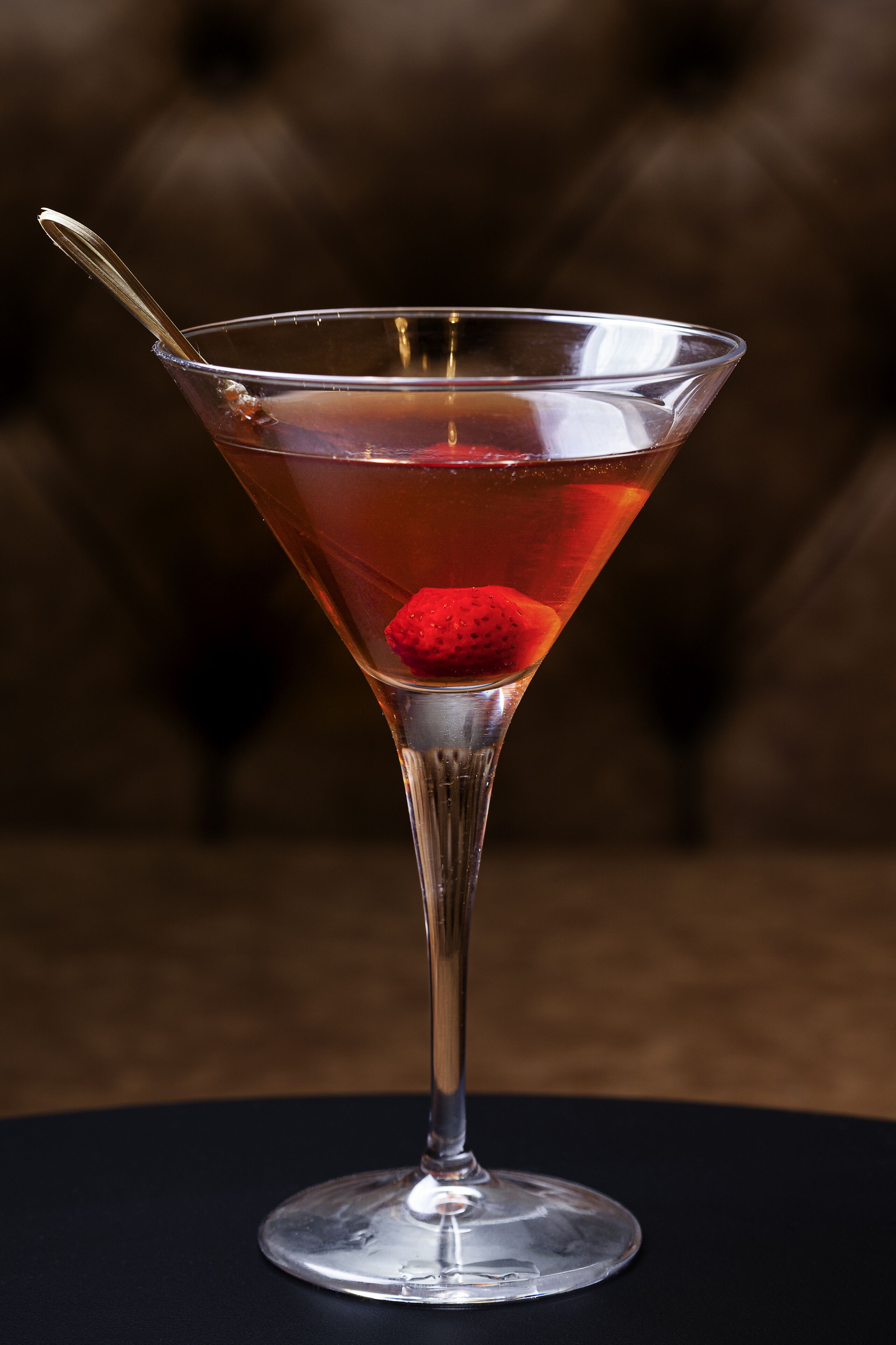 Un got de martini amb una guarnició de maduixa sobre una superfície fosca.