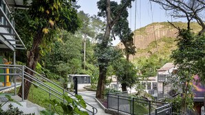 Un sentier menant à un bâtiment entouré d’une végétation luxuriante, avec une montagne en toile de fond.