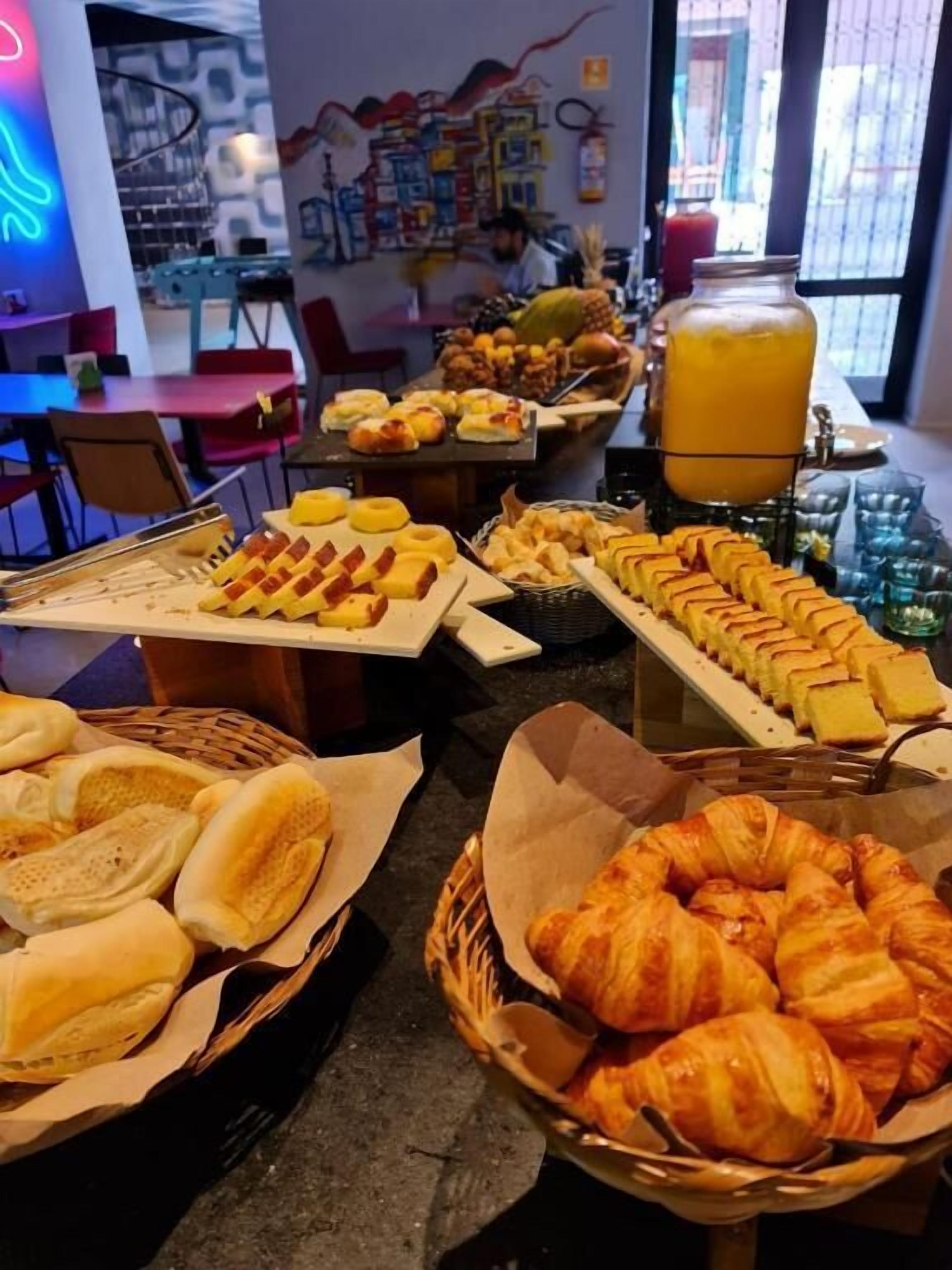 Un bufé de desayuno con pasteles, pan y una presentación de frutas.