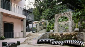 Une cour avec un escalier en pierre, un espace détente avec des coussins à rayures et une table avec des chaises.