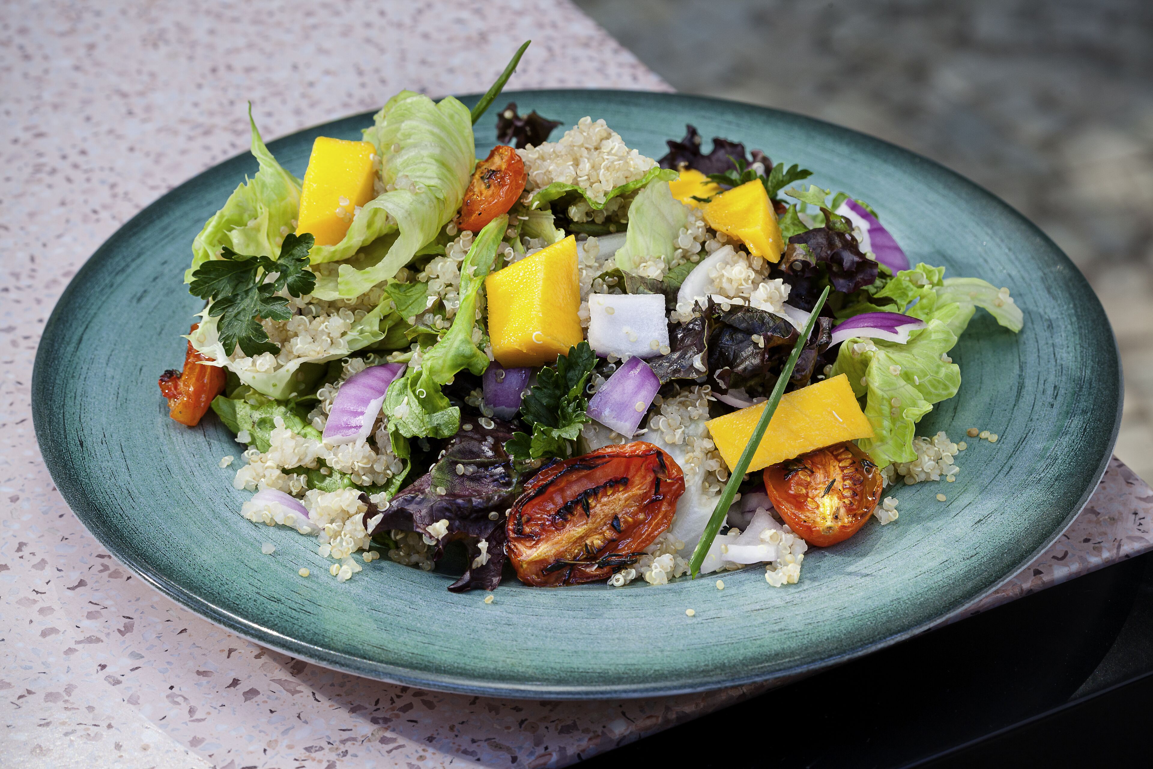A plate of quinoa salad with tomatoes, lettuce, and cheese.
