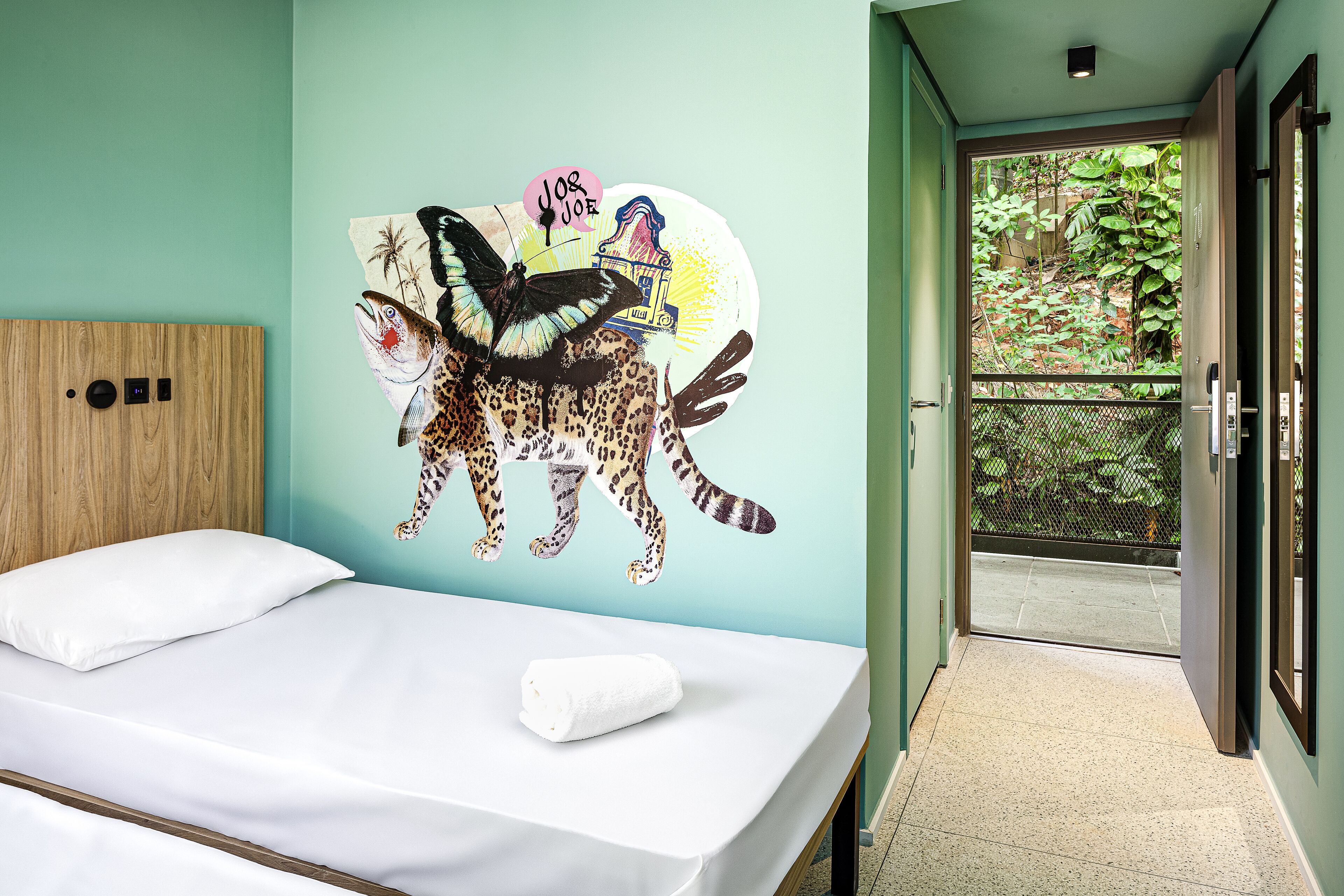 A bedroom with a bed, a leopard mural on the wall, and a view of a balcony.