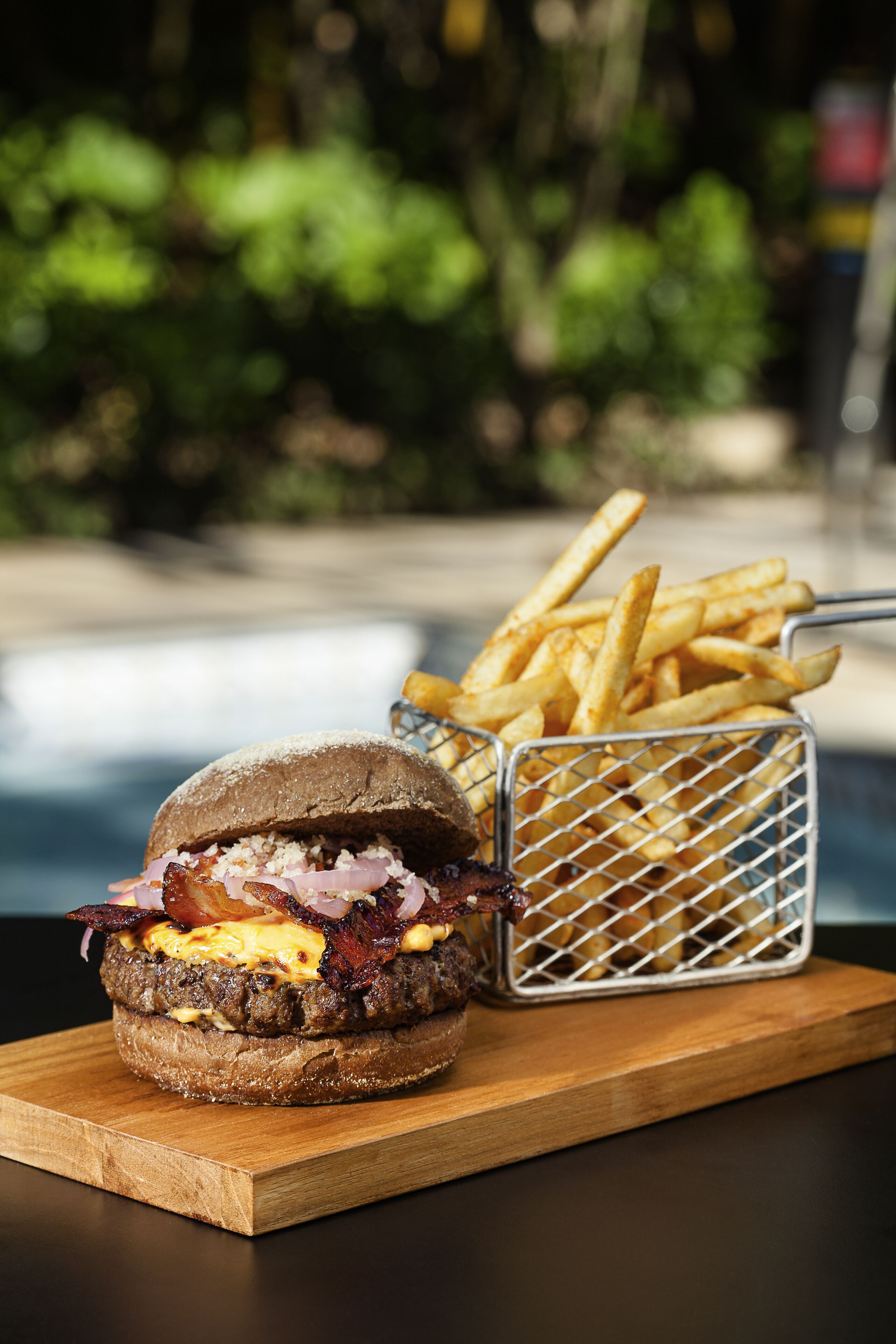 Un hamburger accompagné de frites, le tout servi sur une planche en bois.