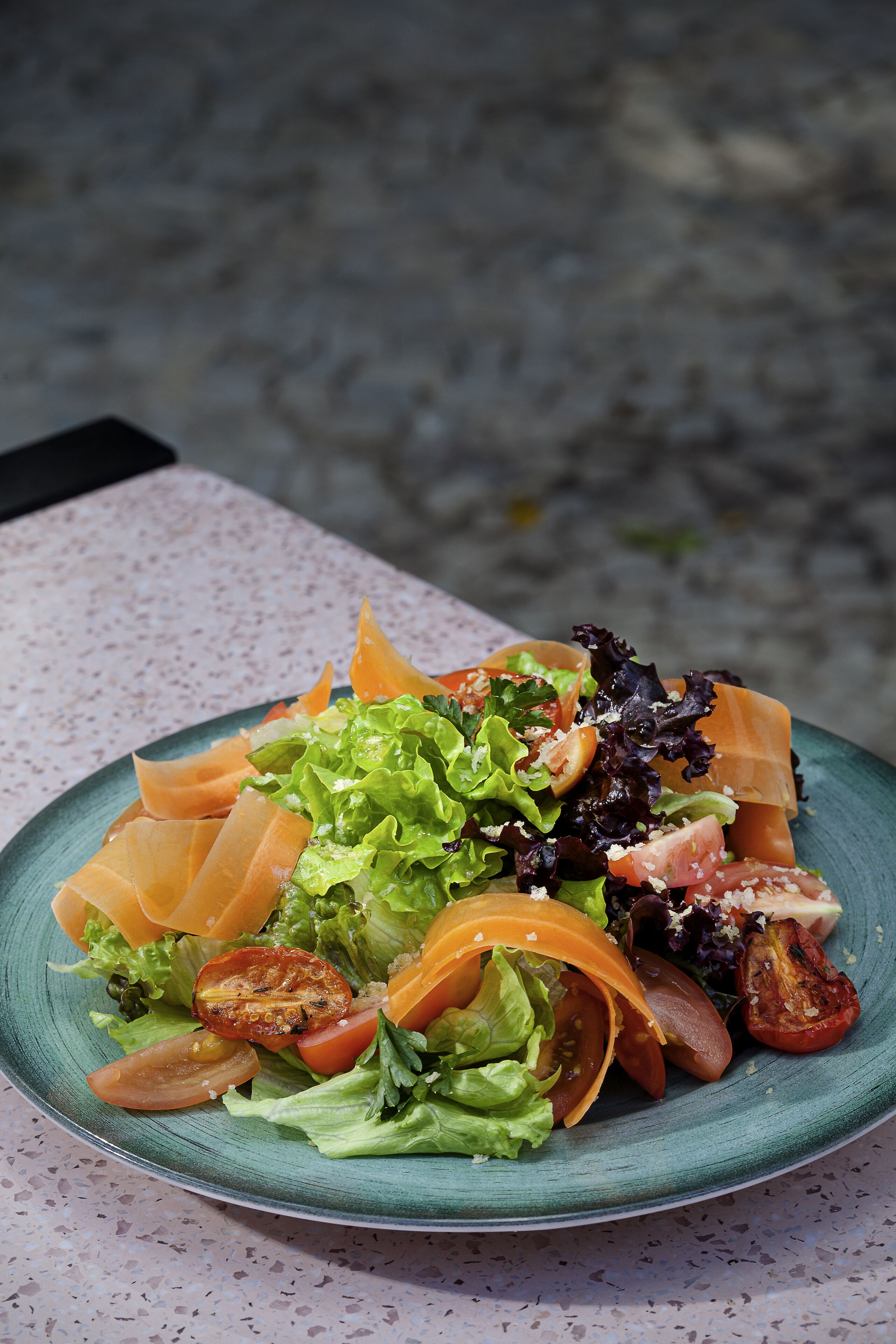 Een bord met gemengde groene salade en groenten op een tafel.