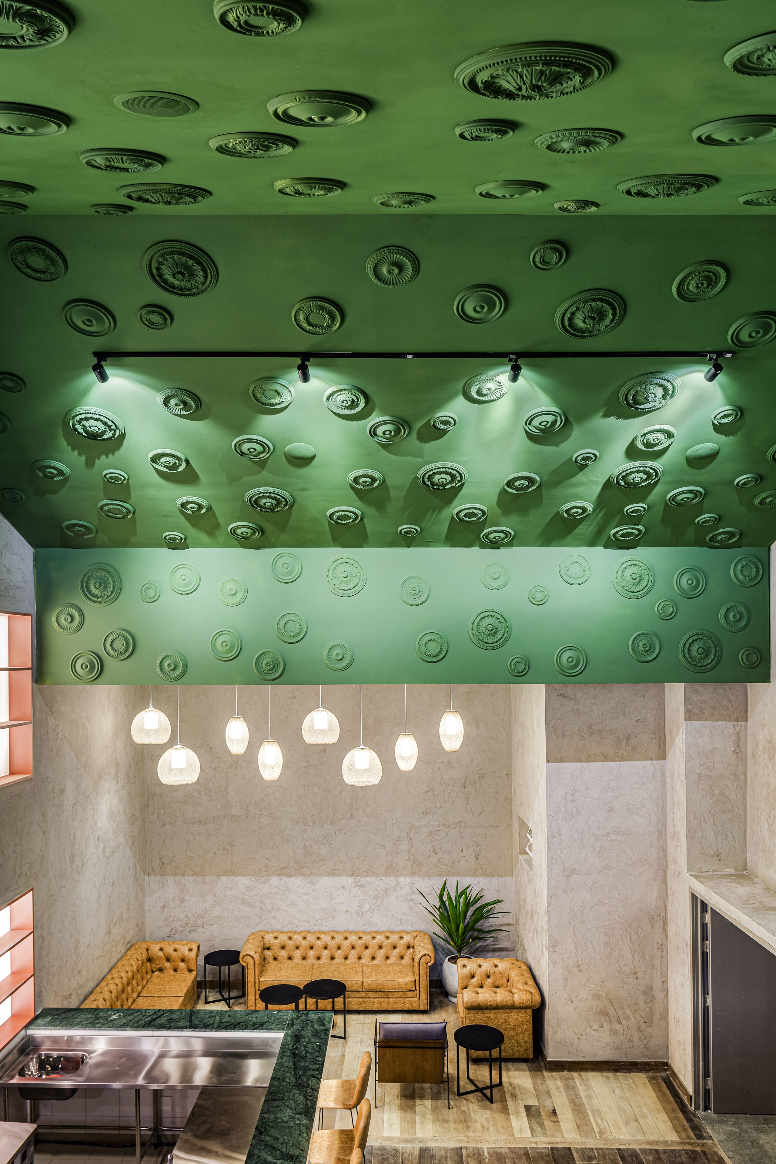A modern interior with a green ceiling, a seating area with a sofa and chairs, and a bar area with a marble countertop.