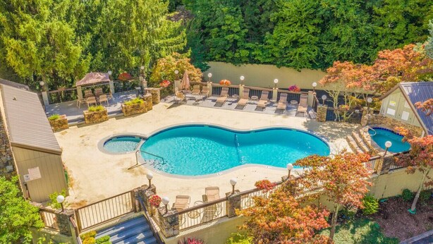 A backyard with a swimming pool, lounge chairs, and a small deck area.