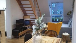 Ein modernes Wohnzimmer mit einem Holzesstisch, einer Treppe, einem Sofa und einem Fernseher.