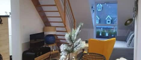 En moderne stue med et træspisebord, trapper, en sofa og et fjernsyn.