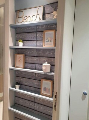 A wall with a wooden panel design and a shelf with decorative items.