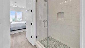 Une salle de bain moderne avec une douche à parois de verre et un sol carrelé.