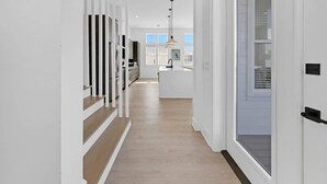 Una cocina moderna con una isla central, iluminación colgante y vistas al exterior.