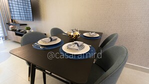 Comedor con una mesa de madera oscura dispuesta para cuatro personas, individuales azules y un centro de mesa decorativo.