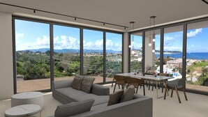 Un soggiorno moderno con un divano ampio, un tavolo da pranzo e vista sul mare e sulle colline.