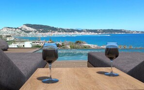 Two wine glasses on a wooden table with a view of a coastal town and sea. - Villa Althea - Villa Althea (Zakynthos)