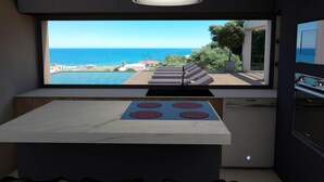 Una cucina moderna con una grande finestra che si affaccia su una piscina e sul mare.