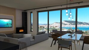 Un soggiorno moderno con un'ampia televisione, un caminetto e un'area pranzo con vista sul mare.