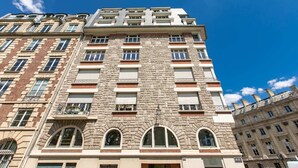 A multi-story building with a stone facade, multiple balconies, and arched windows.