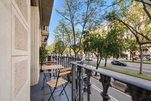 Een balkon met zitplaatsen buiten, uitzicht op de straat en gebouwen op de achtergrond.