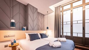 Camera d'albergo moderna con un letto grande, due comodini, un tavolino e una finestra con tende.