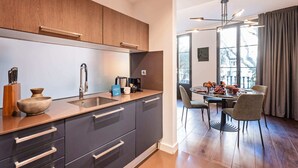 Una cucina moderna con mobili scuri, un lavello in acciaio inossidabile e un'area pranzo con un tavolo imbandito per due.