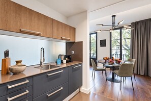 Een moderne keuken met donkere kastjes, een roestvrijstalen spoelbak en een eethoek met een tafel voor vier personen.