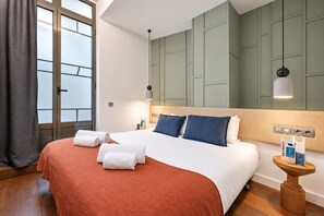 Een hotelkamer met een groot bed, een nachtkastje, een wandlamp en een raam met gordijnen.
