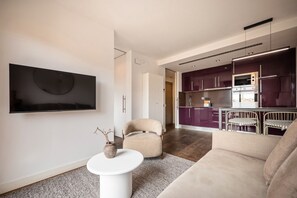 A modern living room with a flat-screen TV, a beige sofa, a small white table, and a vase with branches. - Sweett | Palau 601 - One Bedroom Apartment, Sleeps 3 (Barcelona)