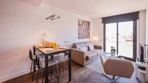 A modern living room with a dining area, a sofa, a coffee table, and a TV. - Sweett | Palau 601 - One Bedroom Apartment, Sleeps 3 (Barcelona)