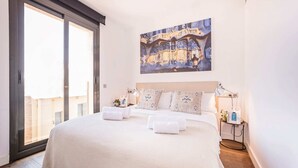 A hotel room with a large bed, a painting of a building, a bedside table with a lamp, and a view of the outside. - Sweett | Palau 601 - One Bedroom Apartment, Sleeps 3 (Barcelona)