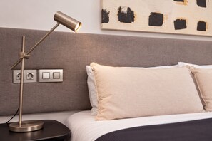 Ein modernes Schlafzimmer mit einem Bett, einer Nachttischlampe und einer Wandsteckdose.