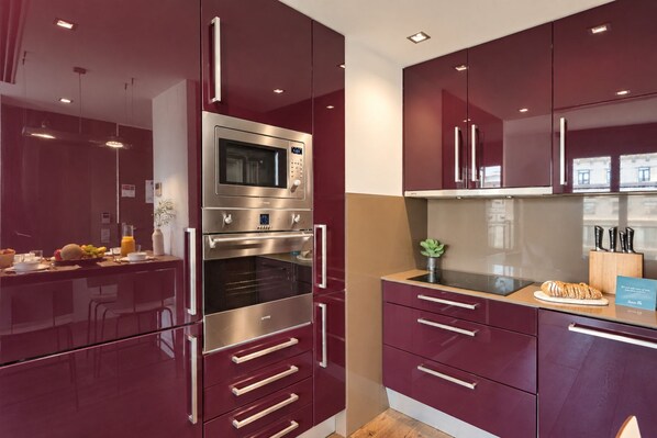 A modern kitchen with stainless steel appliances, maroon cabinetry, and a wooden countertop. - Sweett | Palau 602 - One Bedroom Apartment, Sleeps 3 (Barcelona)
