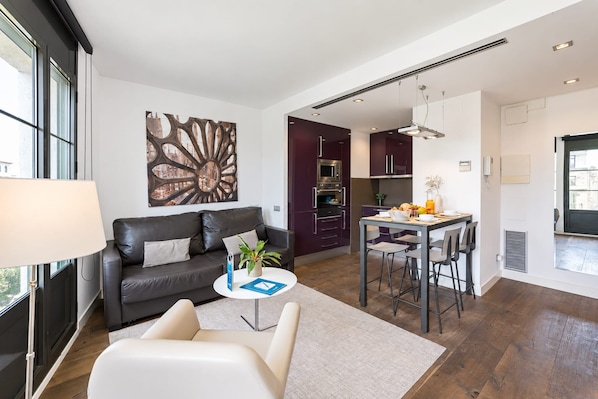 A modern living room with a sofa, a coffee table, and a dining area with a table and chairs. - Sweett | Palau 602 - One Bedroom Apartment, Sleeps 3 (Barcelona)