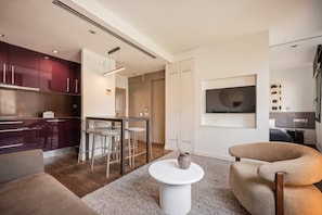 A modern living room with a sofa, a round coffee table, and a TV mounted on the wall. - Sweett | Palau 602 - One Bedroom Apartment, Sleeps 3 (Barcelona)