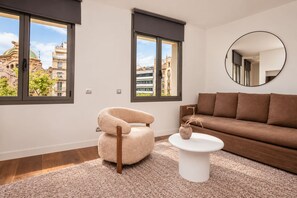Ein modernes Wohnzimmer mit einem braunen Sofa, einem runden Spiegel und einem beigen Sessel.